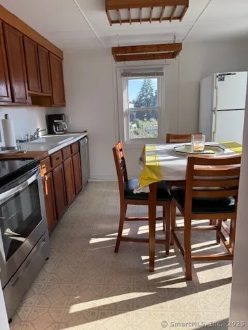 a kitchen with stainless steel appliances kitchen island granite countertop a stove a sink a dining table and chairs