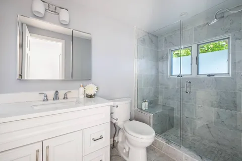 a bathroom with a toilet a sink a window and mirror