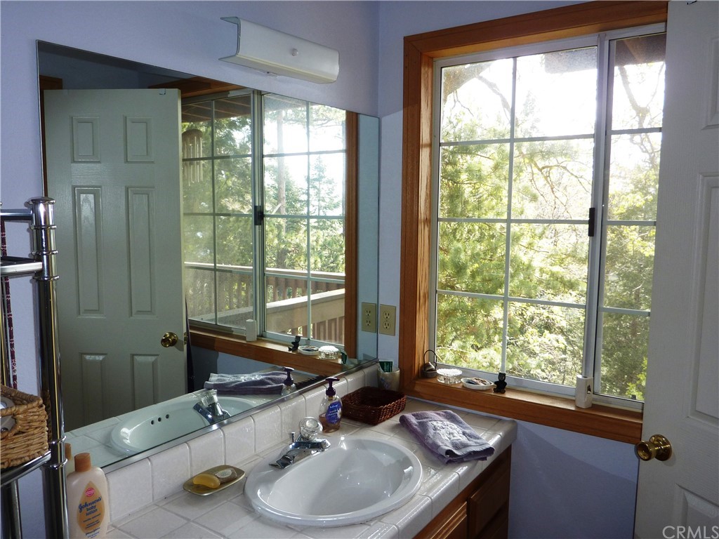 25274 N Road Twin Peaks, CA 92391 - Photo 23 of 35 a bathroom with a granite countertop sink and a large mirror next to a window