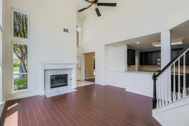 a view of an empty room with wooden floor fireplace and a window