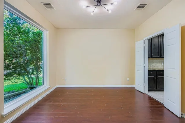 an empty room with wooden floor fan and windows