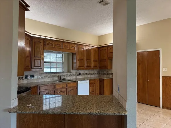 a kitchen with kitchen island granite countertop a sink and a refrigerator