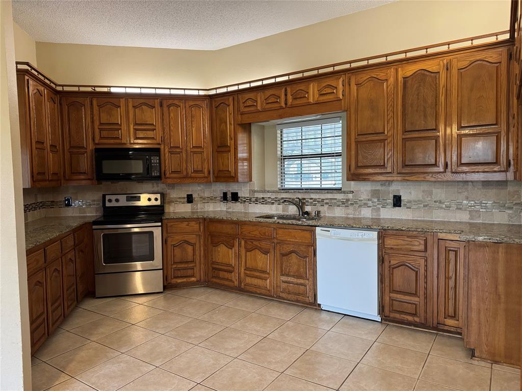 116 Ridge Crest Street Red Oak, TX 75154 - Photo 8 of 18 a kitchen with stainless steel appliances granite countertop a stove a sink and a microwave