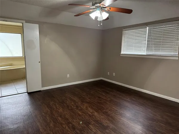 an empty room with wooden floor chandelier fan and windows