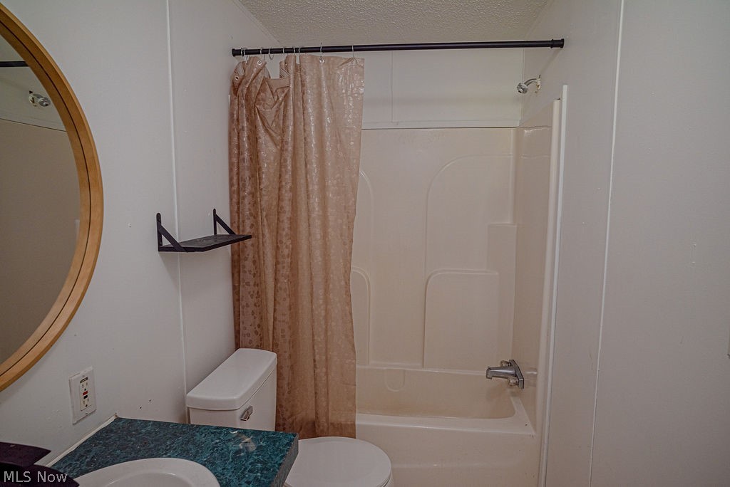 967 Buck Run Road Mineral Wells, WV 26150 - Photo 30 of 50 Bathroom featuring a tub/shower combination with a single-handle faucet, a toilet, a vanity with an integrated sink and a green patterned countertop, and a circular mirror with a light wood-finish frame