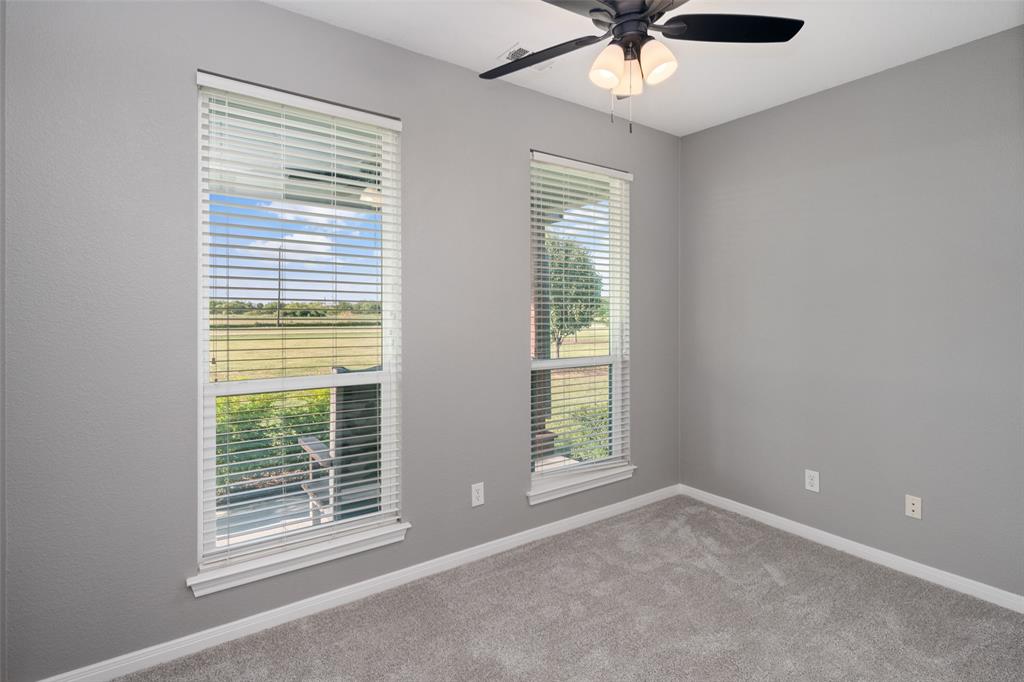 1019 Vaughan Lane Tioga, TX 76271 - Photo 25 of 40 Bedroom featuring two windows with horizontal blinds, gray wall paint, and gray carpet flooring