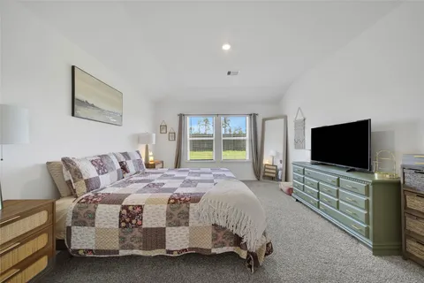 a spacious bedroom with a bed and a flat screen tv