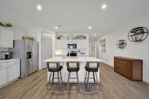 a kitchen with stainless steel appliances a dining table chairs refrigerator and sink