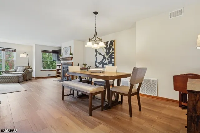 a dining room with wooden floor a chandelier a wooden table and chairs