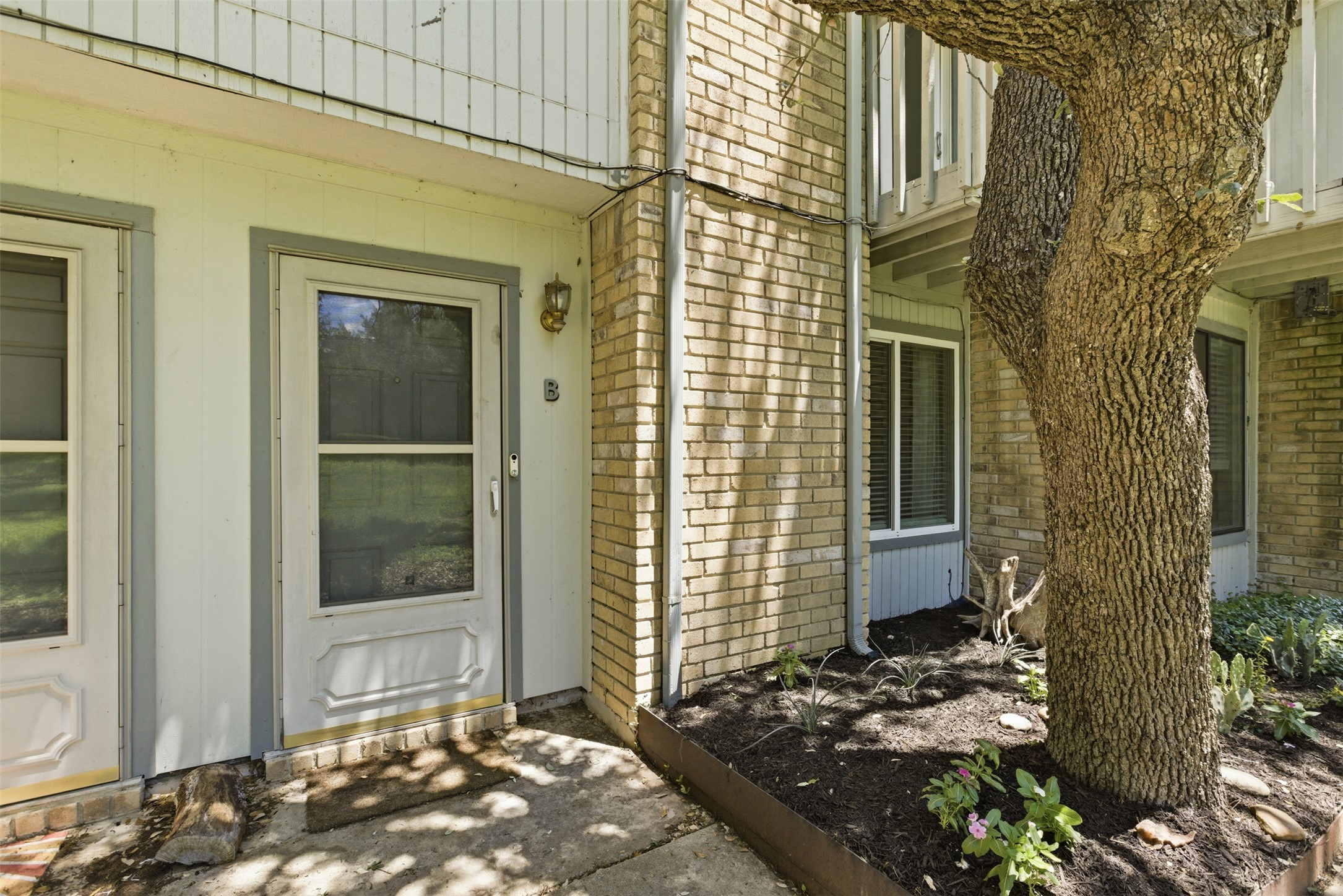 4204 Hudson Bend Road, Unit B Austin, TX 78734 - Photo 3 of 37 Entryway featuring light brick facade, white siding, and a large mature tree