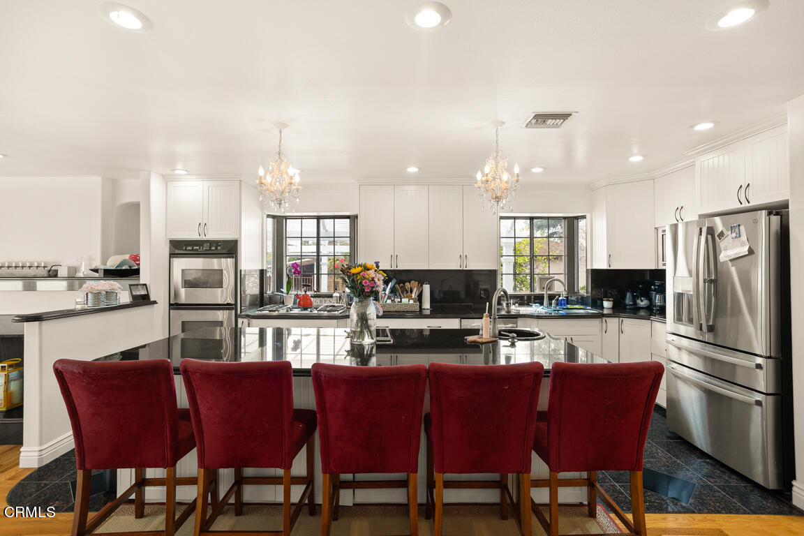 4900 Crown Avenue La Canada Flintridge, CA 91011 - Photo 10 of 41 a kitchen with stainless steel appliances granite countertop a dining table chairs refrigerator microwave and cabinets