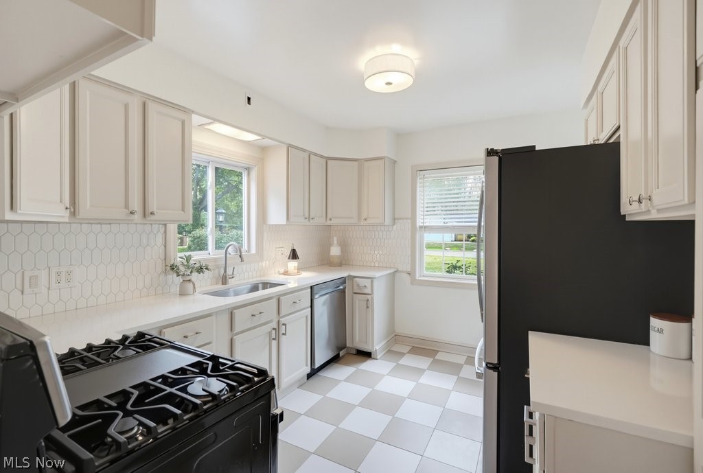 2468 Ridgewood Road Akron, OH 44313 - Photo 20 of 50 White cabinetry, white countertops, stainless steel sink, black range, and checkered flooring