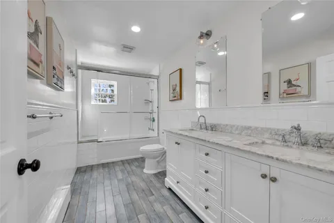 a bathroom with a granite countertop sink a toilet a mirror and shower