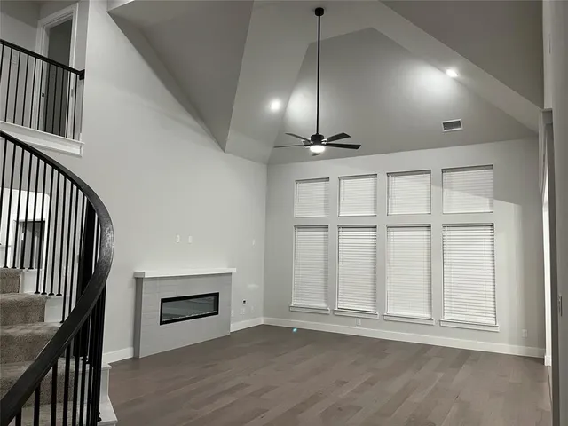 an empty room with wooden floor fan and windows