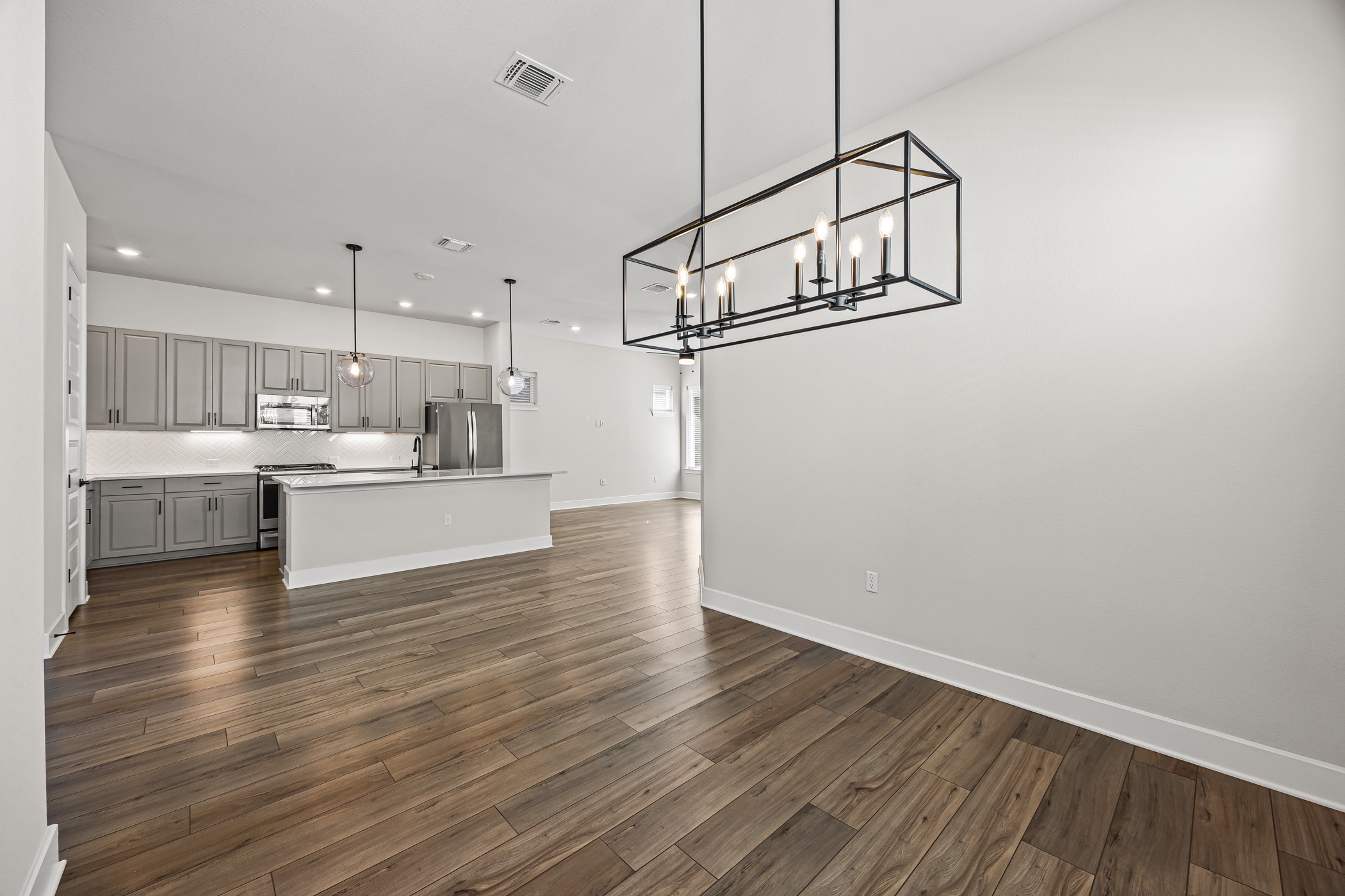 5806 Rangeland Road Austin, TX 78747 - Photo 34 of 34 An open floor plan seamlessly connects the kitchen and living spaces, featuring hardwood floors and modern fixtures.