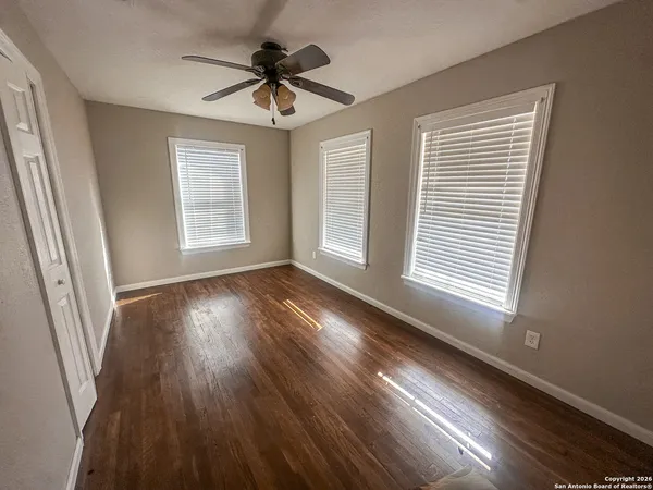 a view of an empty room with wooden floor and a window