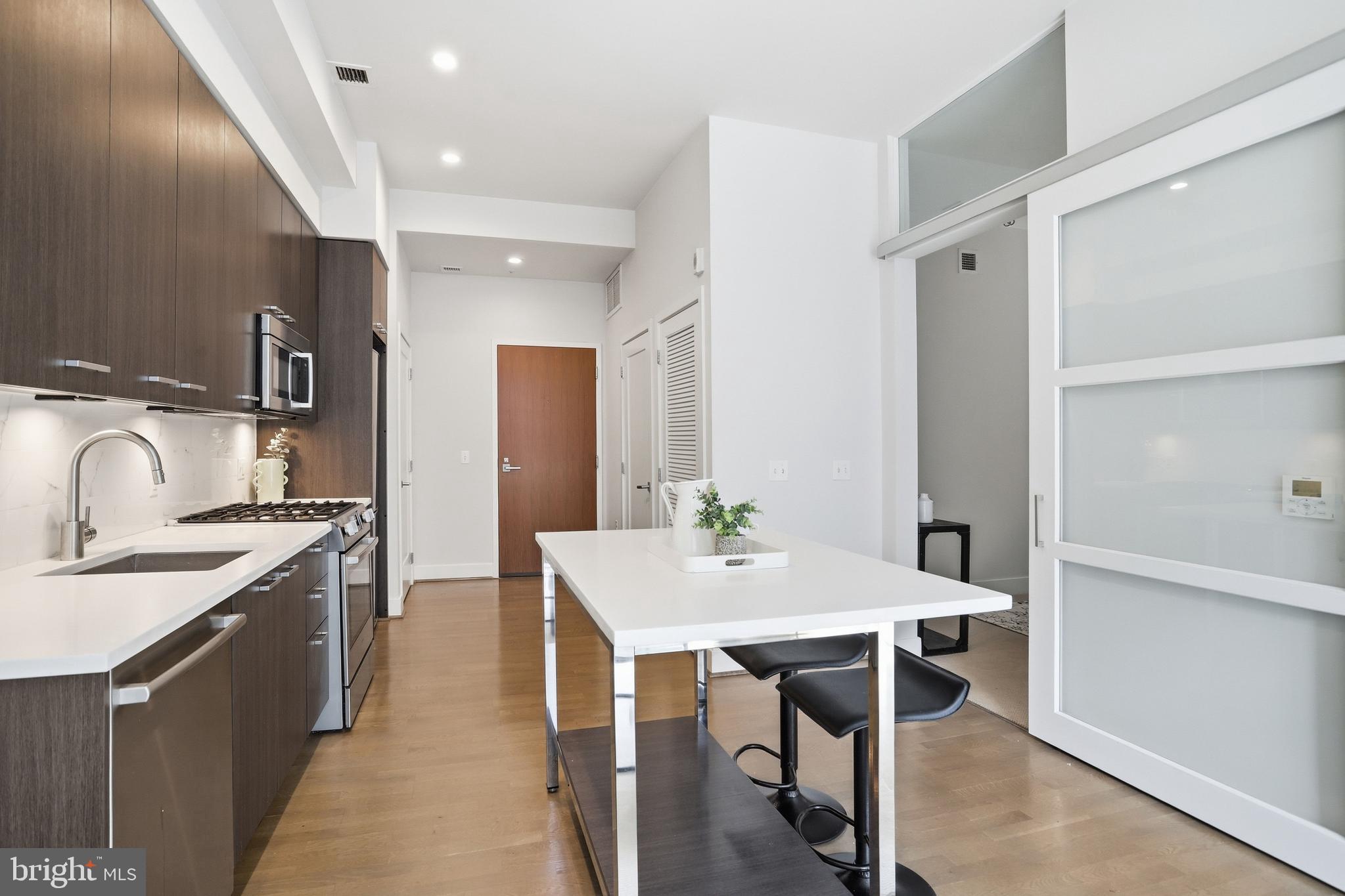 525 Water Street Southwest, Unit 311 Washington, DC 20024 - Photo 11 of 53 a view of a kitchen area with furniture and wooden floor