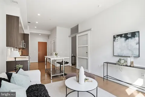 a living room with stainless steel appliances furniture a dining table and kitchen view