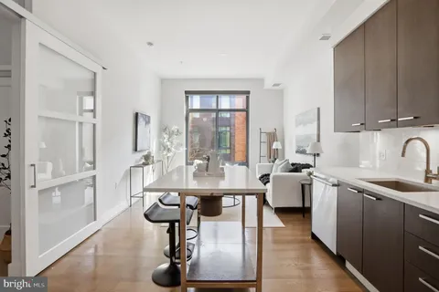 a kitchen with stainless steel appliances kitchen island granite countertop a table chairs in it and wooden floors