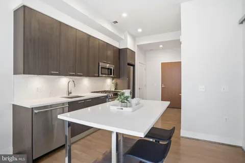 a kitchen with a sink a stove a refrigerator cabinets and a dining table