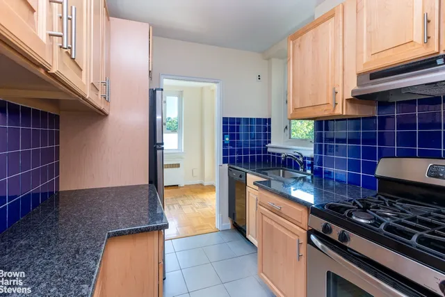 a kitchen with granite countertop a stove a sink and white cabinets