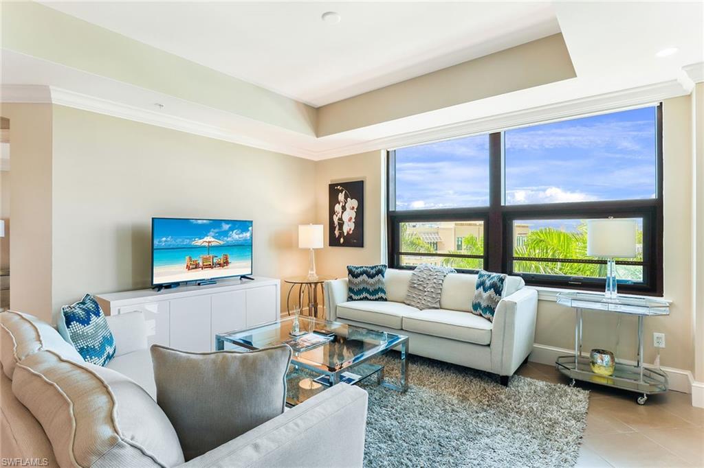 9115 Strada Place, Unit 5414 Naples, FL 34108 - Photo 4 of 26 a living room with furniture a flat screen tv and a large window