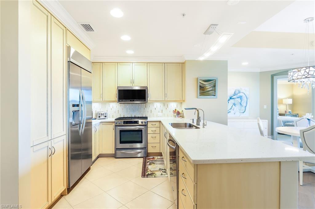 9115 Strada Place, Unit 5414 Naples, FL 34108 - Photo 7 of 26 a kitchen with a sink a kitchen island and stainless steel appliances