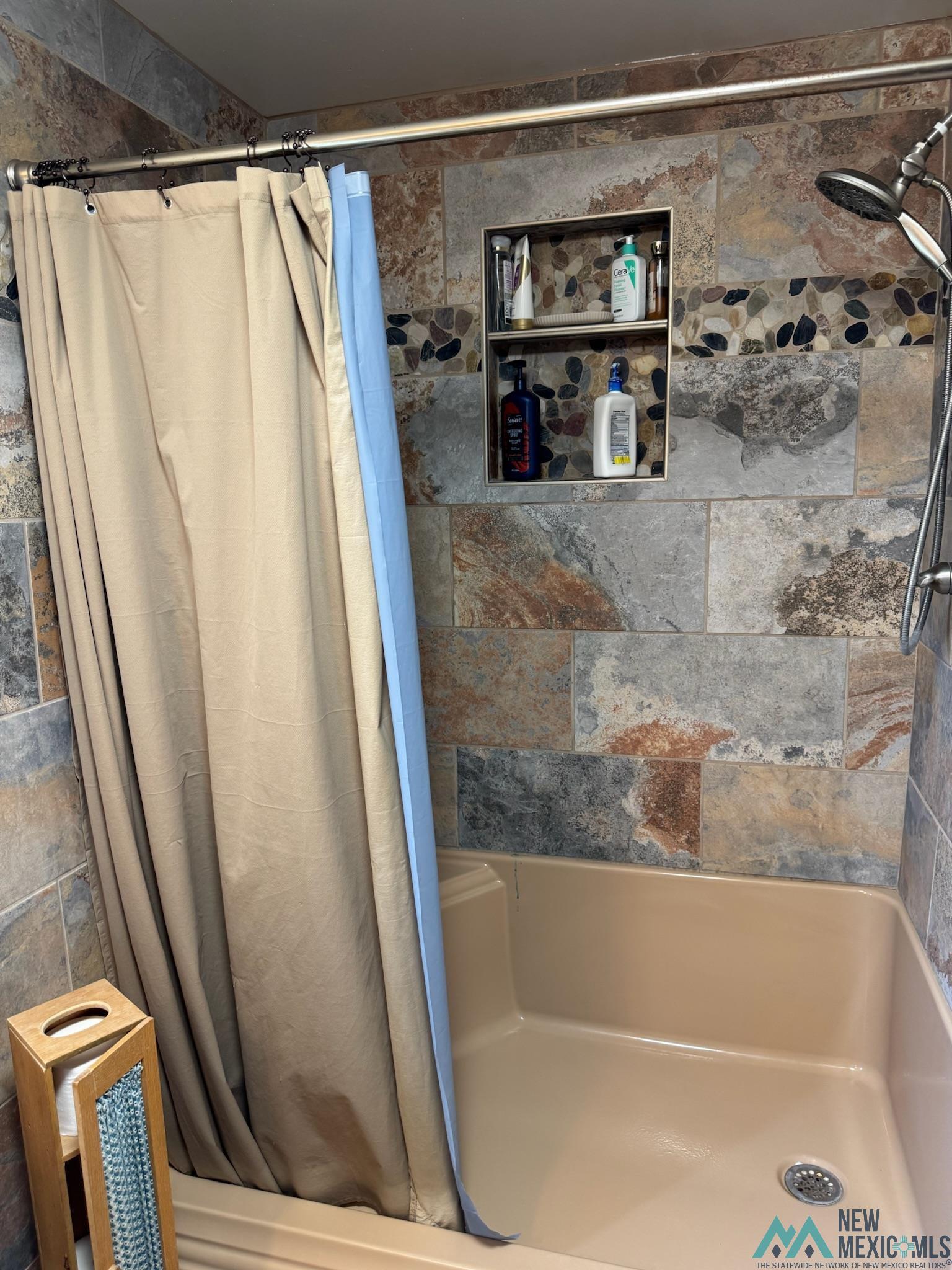 6660 Cherokee Road Dexter, NM 88230 - Photo 12 of 46 Shower enclosure with variegated stone-finish tile surround, integrated shower niche, and mosaic pebble accent strip