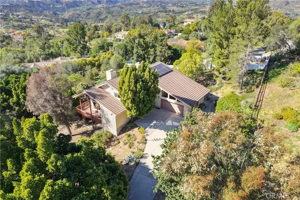 an aerial view of residential house with outdoor space and trees all around