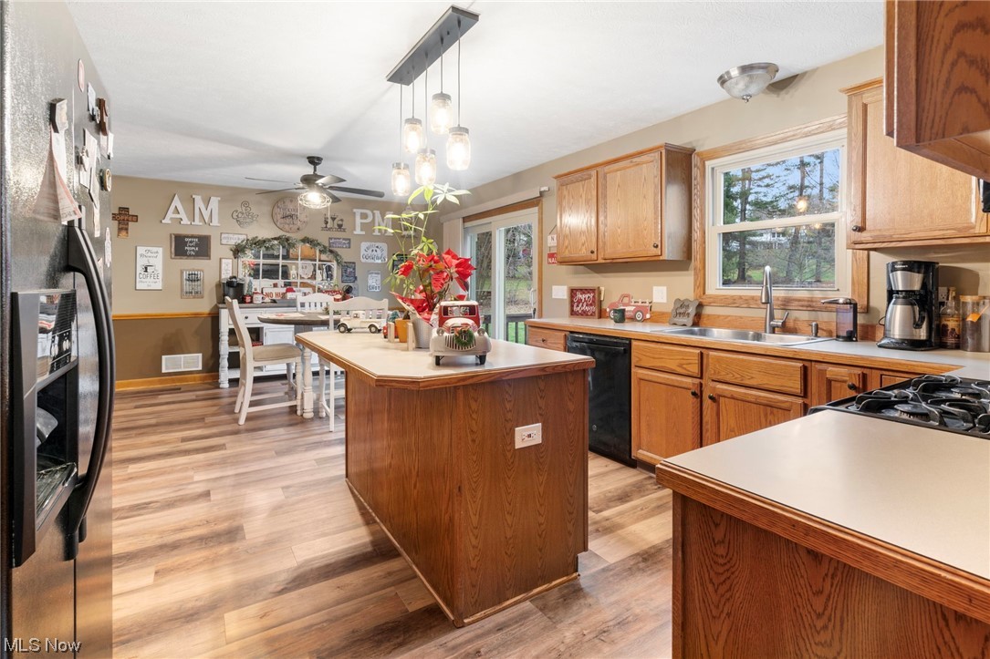 4915 Monticello Street Northwest Canton, OH 44708 - Photo 12 of 31 Kitchen with a center island, light hardwood / wood-style flooring, ceiling fan with notable chandelier, pendant lighting, and black appliances
