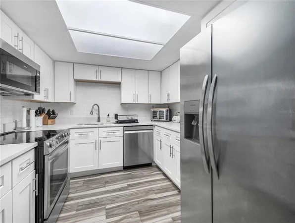 a kitchen with stainless steel appliances granite countertop a refrigerator a stove and a sink with wooden floor