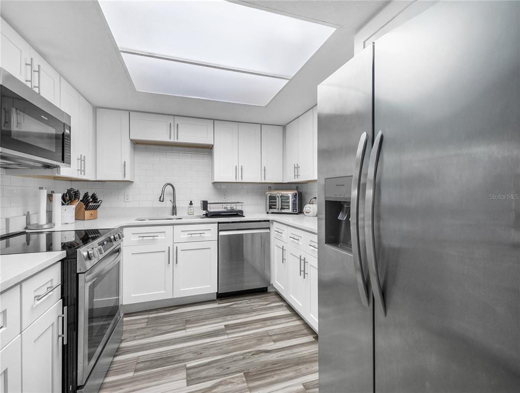 622 Fairways Circle, Unit A Ocala, FL 34472 - Photo 4 of 26 a kitchen with stainless steel appliances granite countertop a refrigerator a stove and a sink with wooden floor