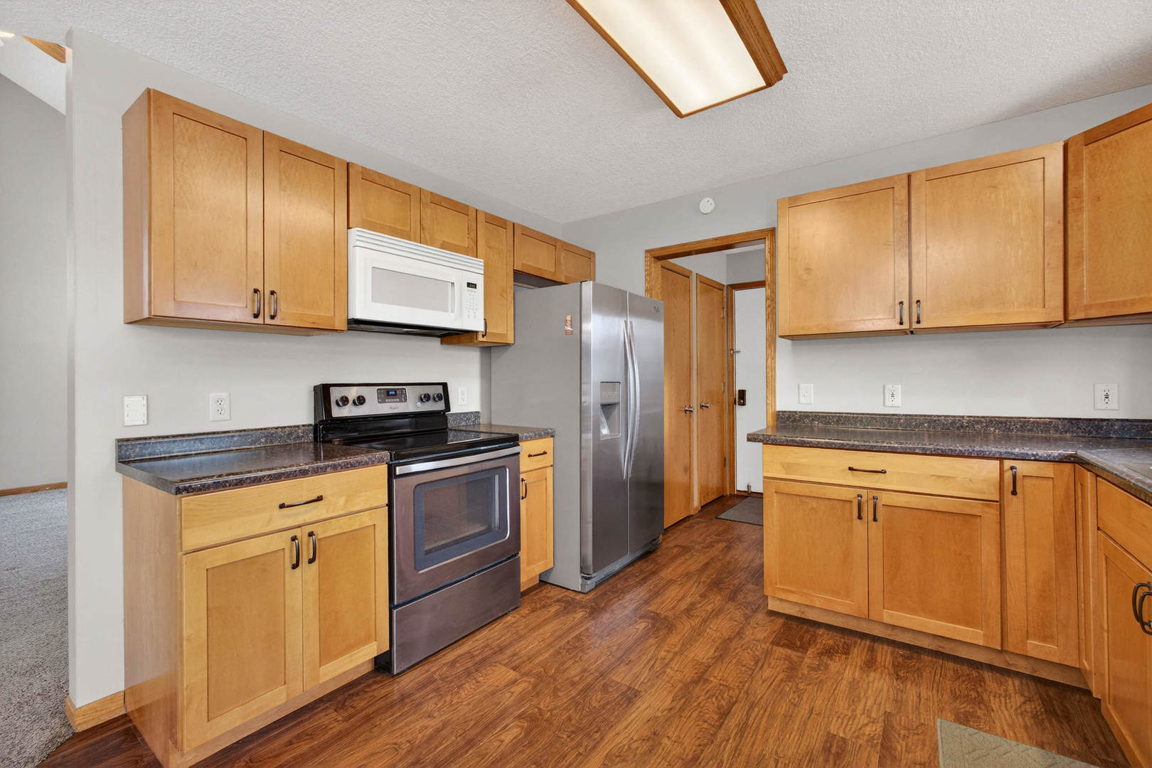 313 Sullivan Drive Colona, IL 61241 - Photo 10 of 41 a kitchen with stainless steel appliances granite countertop wooden cabinets a sink a stove a refrigerator and microwave with wooden floor