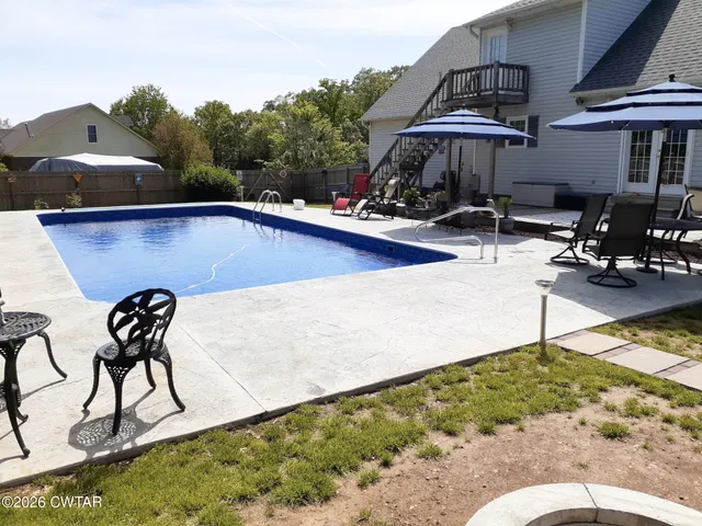 a view of swimming pool with seating area and trees in the background