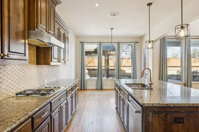 a kitchen with granite countertop a sink a counter top space and stainless steel appliances
