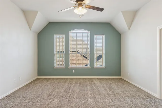 an empty room with chandelier fan and windows