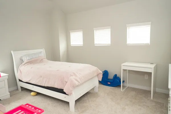 a bedroom with a bed and a computer on a desk next to a window