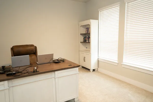 an empty room with windows and chandelier fan
