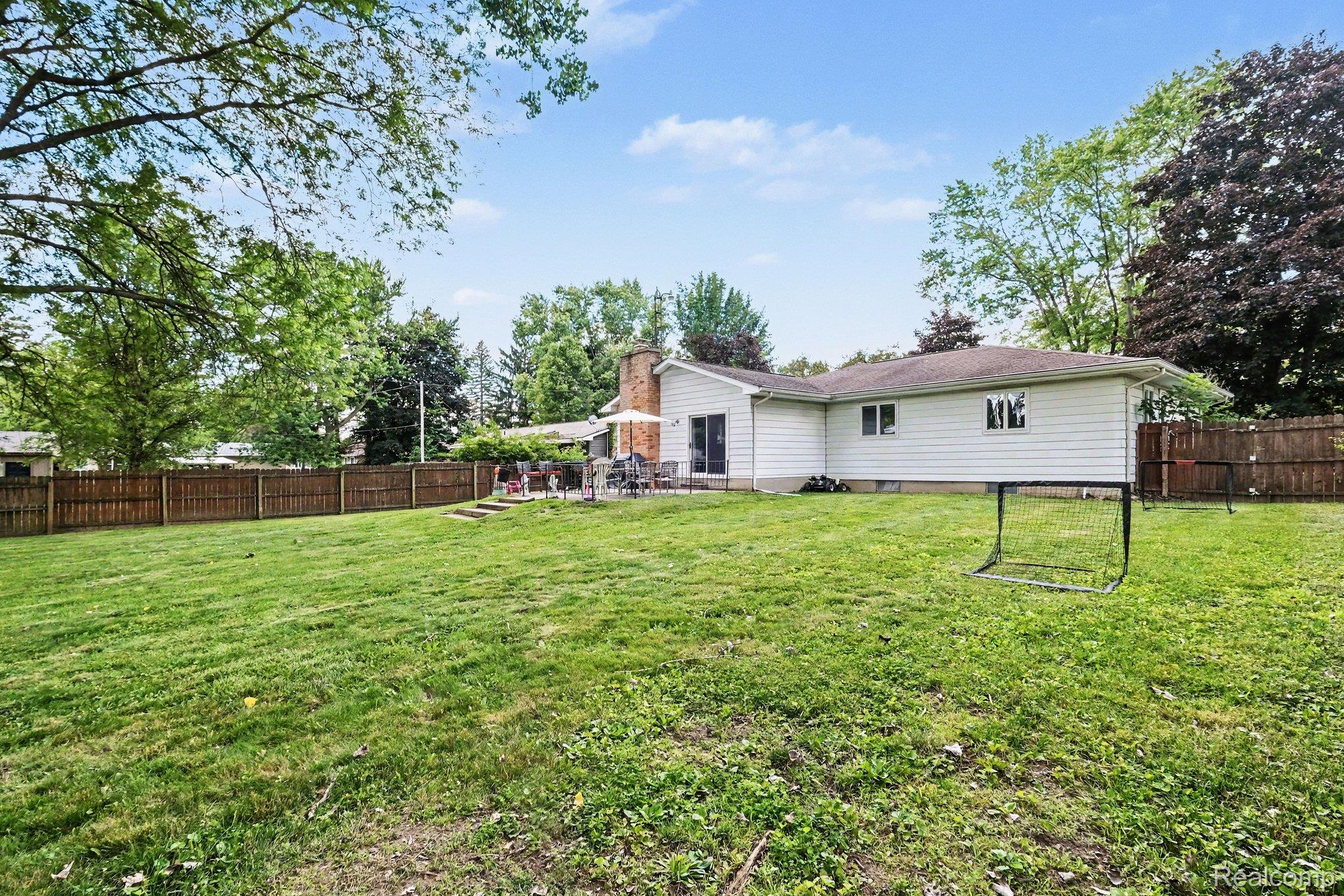5449 South Genesee Road Grand Blanc, MI 48439 - Photo 17 of 18 Expansive backyard featuring a manicured lawn, a full privacy fence, mature trees, a patio, and exterior siding
