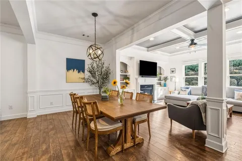 a dining room with wooden floor a chandelier a glass table and chairs