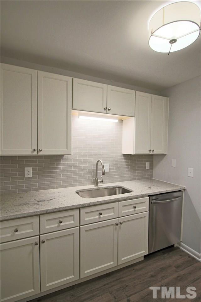 5815 Shady Grove Circle Raleigh, NC 27609 - Photo 6 of 19 a kitchen with a sink dishwasher a stove and white cabinets