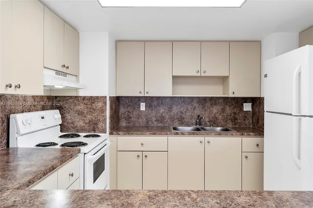 a kitchen with granite countertop a sink stove and refrigerator