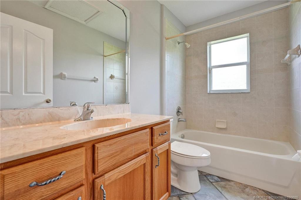 5902 Yucca Drive Fort Pierce, FL 34982 - Photo 21 of 83 a bathroom with a granite countertop sink toilet a large mirror and a bathtub