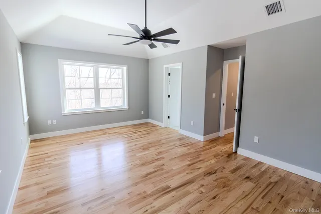 a view of empty room with wooden floor and ceiling fan