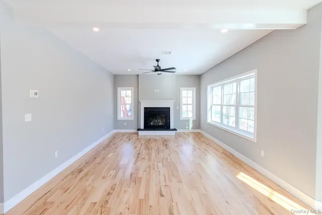 an empty room with wooden floor fireplace and windows