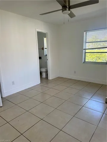 an empty room with a ceiling fan and window