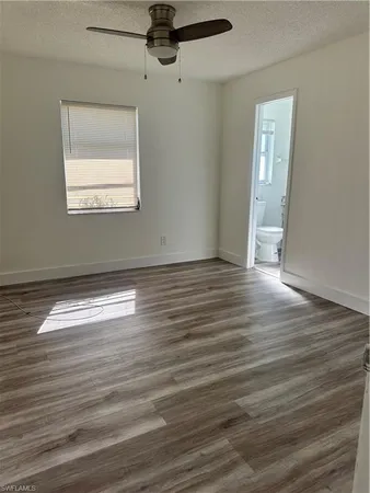 an empty room with wooden floor chandelier fan and windows