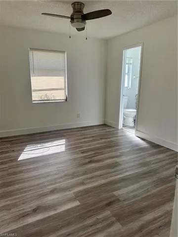 an empty room with wooden floor chandelier fan and windows