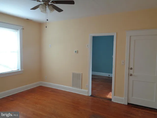 an empty room with wooden floor fan and windows