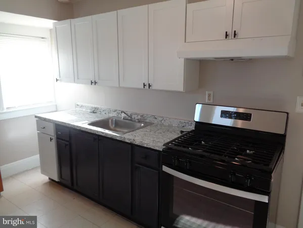 a kitchen with granite countertop white cabinets and black stove top oven